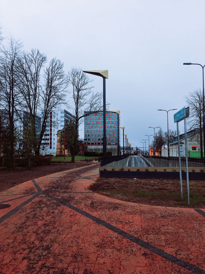 A city walkway flanked by modern buildings under an overcast sky.
