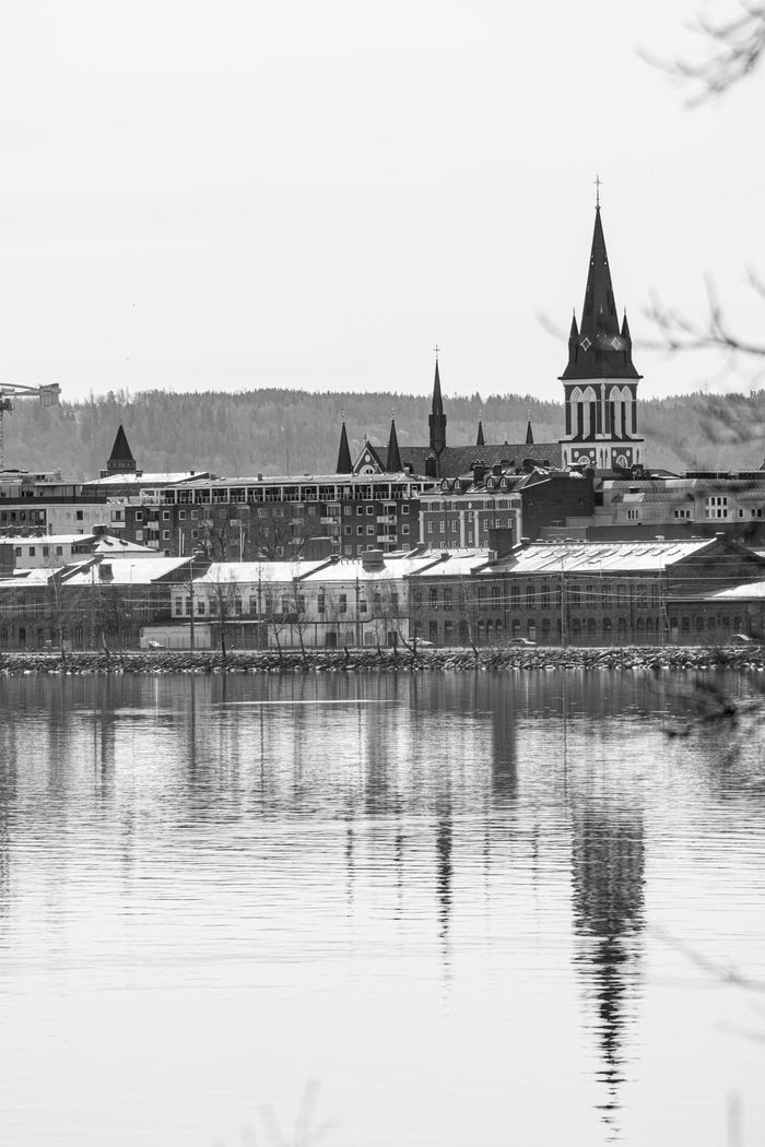 Explore the serene black and white cityscape of Jönköping, Sweden, with church towers reflecting on a calm lake.