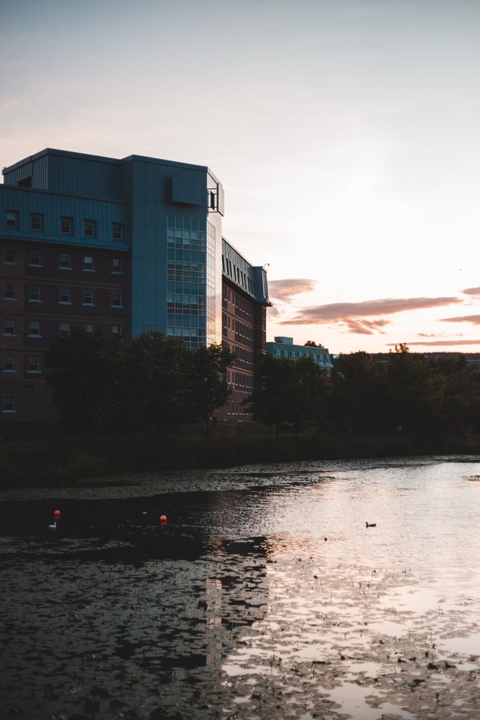 Modern building exterior reflecting on a calm river at twilight with a serene atmosphere.
